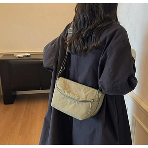 Detail of olive green nylon crescent bag with adjustable strap and metal zipper