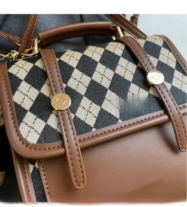 Macro detail of diamond lattice fabric with brown leather trim and golden metal hardware