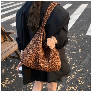 Detailed view of oversized leopard print tote bag with plush bear charm on a female model