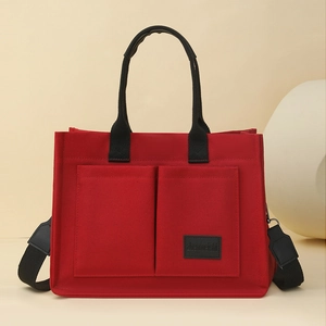Vue détaillée du sac fourre-tout en toile rouge avec poches avant et bandoulière noire réglable
