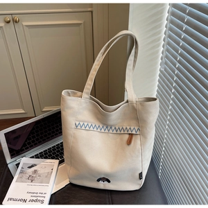 Close-up of minimalist canvas tote bag featuring blue zigzag stitching and dog embroidery