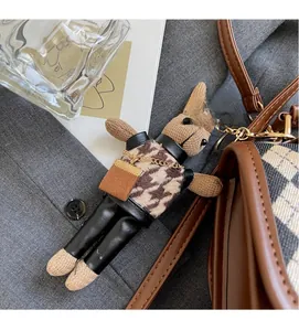 Detailed shot of knitted rabbit charm with houndstooth vest and gold chain bag accessory
