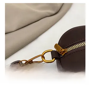Detail view of premium gold-tone metal hooks and dark brown textured leather texture