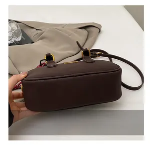 Detail view of deep brown bowling bag base with golden hardware and red woven strap trim
