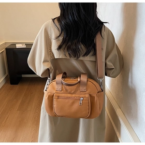 Caramel nylon tote bag with multi-pocket design shown on model wearing beige trench coat