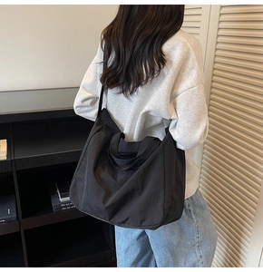 Vue détaillée du grand sac cabas noir avec une large bandoulière ajustable sur le mannequin