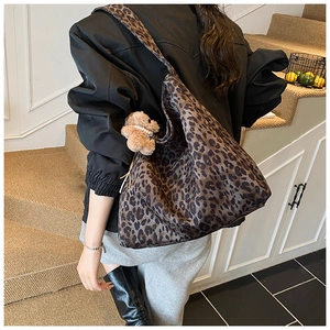 Detail of vintage leopard print hobo bag with plush bear charm on wide shoulder strap