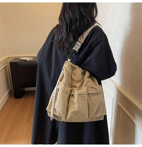 Detailed view of a khaki nylon crossbody bag featuring drawstring closure and cargo pockets