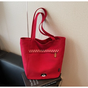 Detail of red canvas tote bag featuring wave embroidery and a cute cartoon dog motif