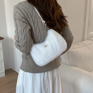 Détail d'un sac à bandoulière en fausse fourrure blanche porté par un mannequin chez soi