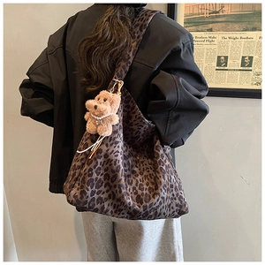 Detail of vintage leopard print tote bag with cute plush bear charm on wide shoulder strap