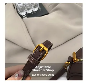 Detail of adjustable leather shoulder strap with gold metal buckle on brown boston bag