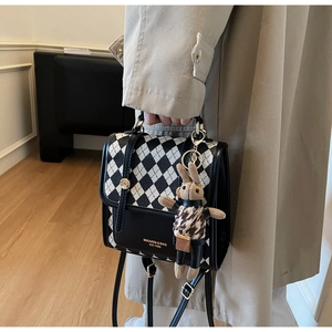 Detail of checkered crossbody bag with leather trim and cute rabbit doll pendant
