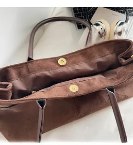 Detail view of large brown suede tote bag with golden magnetic clasp and inner zip pocket
