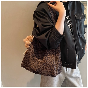 Detail of leopard print tote bag with woven handles and a cute plush bear charm
