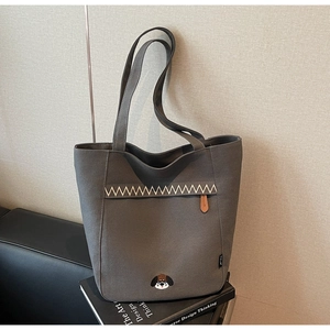 Close-up of gray canvas tote bag featuring beige zigzag stitching and small dog embroidery