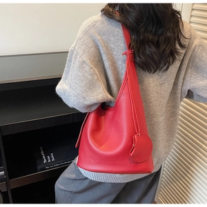 Red lychee textured leather bucket bag worn by model showing large capacity and detail