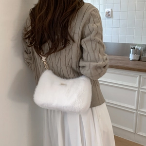 Gros plan sur un sac bandoulière en peluche blanche avec boucle en métal doré chic