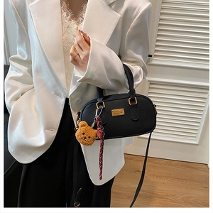 Detail view of black matte leather Boston bag with teddy bear charm and ribbon