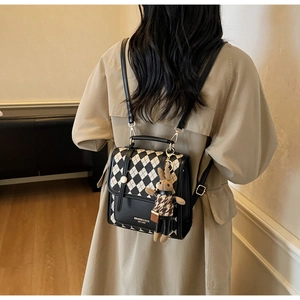 Detailed back view of a black and beige checkered backpack with a cute bunny charm