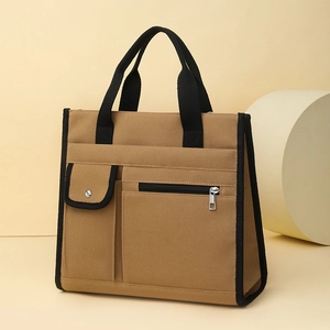 Detail of canvas tote bag with front snap pocket, zipper pocket and two-tone拼接 design