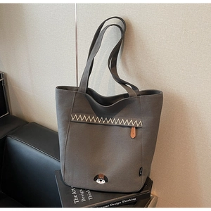 Detail of dark grey canvas tote bag featuring embroidered puppy and white zigzag stitching