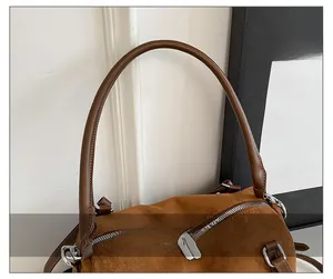 Detail of soft brown suede shoulder bag showing thick leather straps and silver zippers