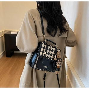 Quilted check backpack with plush bunny charm worn by a model in a warm indoor setting