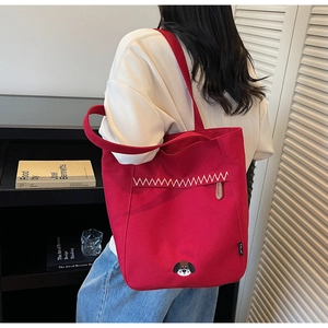 Detail of red canvas tote bag featuring dog embroidery and white zigzag stitching