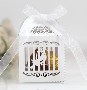 Detailed laser-cut white birdcage wedding favor box with white ribbon and golden chocolate