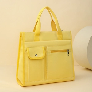 Detail of yellow canvas tote bag featuring buttoned flap pocket and metal zipper pouch