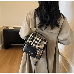 Detail of rhombic pattern crossbody bag with plush rabbit charm and metal clasp