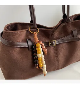 Close-up of retro wooden bead charm with floral patterns on brown suede shoulder bag