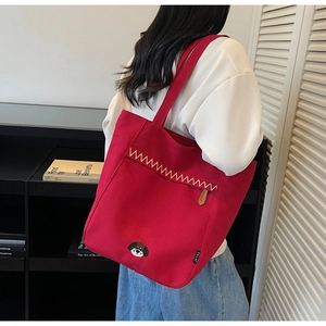 Detail of red canvas tote bag with wave embroidery and cute puppy head patch