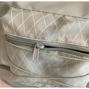 Close-up of smooth nylon zipper and diamond lattice texture on grey-green gym bag