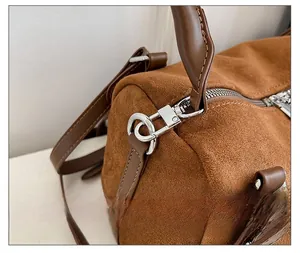 Detailed macro view of silver-tone hardware and brown suede texture on a cylinder bag