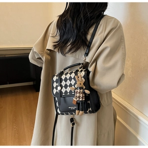 Detail of vintage checkerboard crossbody bag with plush bunny pendant and metal handle