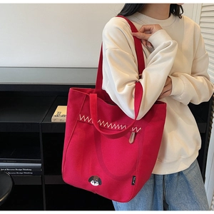 Detail of red canvas tote bag featuring a cute dog embroidery and white wavy stitching