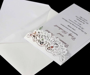 Elegant white laser-cut wedding invitation set with floral patterns and luxury envelopes