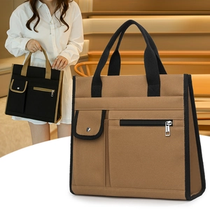Detail view of canvas tote bag showing front zipper pockets and snap button flap pocket
