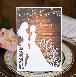 Détail d'invitation de mariage découpée au laser avec silhouettes Mrs & Mrs et carte boisée