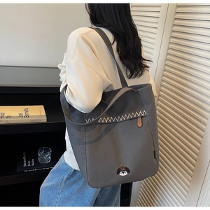 Detail of grey canvas tote bag with puppy embroidery and white zigzag stitching accents