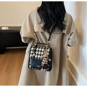 Detail of checkered crossbody bag with cute plush rabbit pendant and gold metal buckle