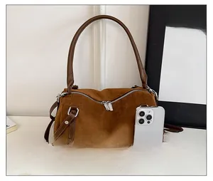 Size comparison of a brown suede shoulder bag next to a smartphone for capacity
