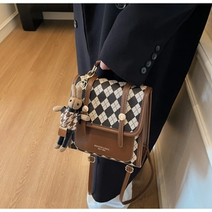 Detail of checkered canvas bag with leather trim and cute rabbit doll keychain