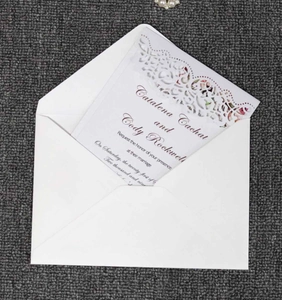 Detail view of laser-cut lace wedding invitation with a matching white V-flap envelope