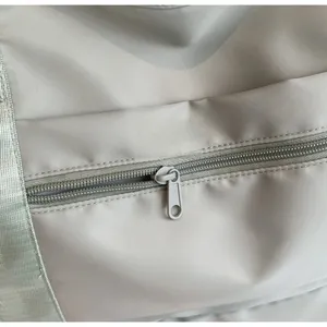 Close-up of smooth metal zipper and durable nylon fabric on the beige travel bag