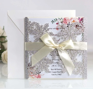 Elegant laser-cut silver snowflake wedding invitation with floral insert and satin ribbon