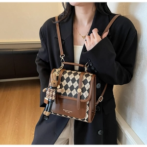 Detail view of retro argyle crossbody bag with rabbit charm on a stylish model