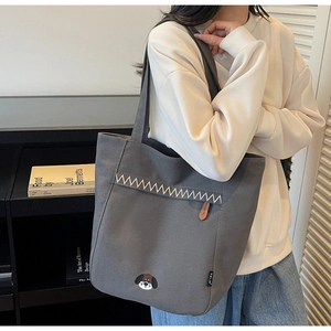 Detail of grey canvas tote bag featuring a cute puppy embroidery and wavy stitching